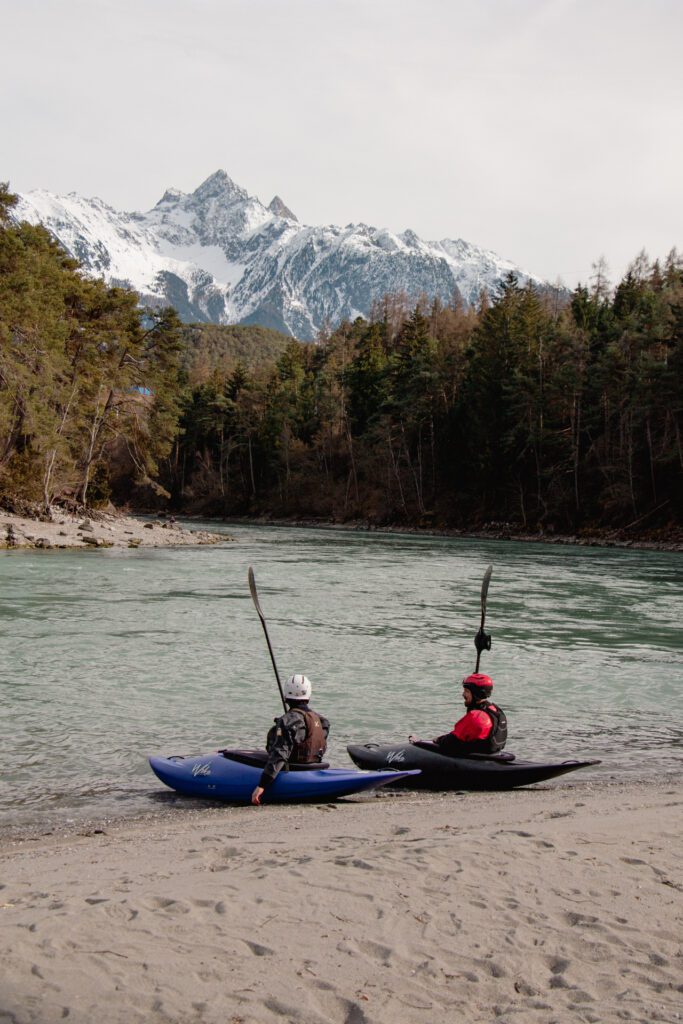 Two kayakers sitting in their kayaks at the shore, about to enter the water.