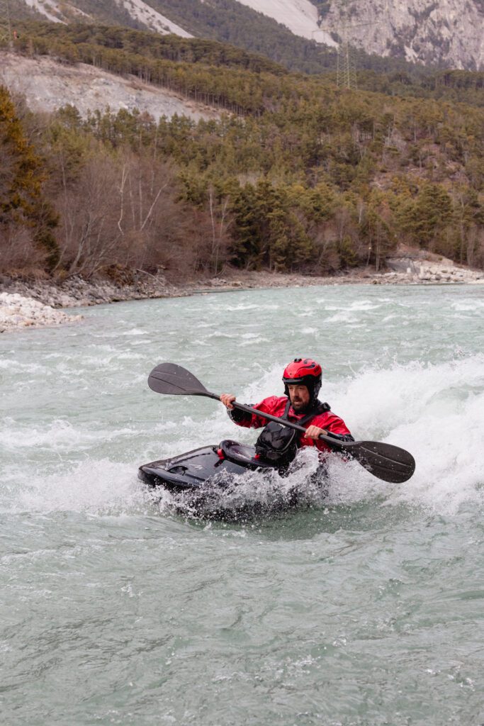 A kayaker in a black Waka Skuxx surfing a small wave.