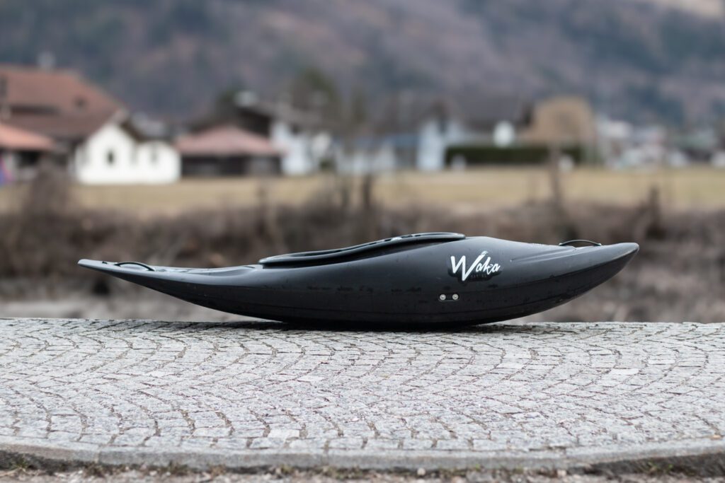 Waka Kayaks Skuxx in black, side view; Short riverrunner kayak with loads of volume in the front and a slicey stern.